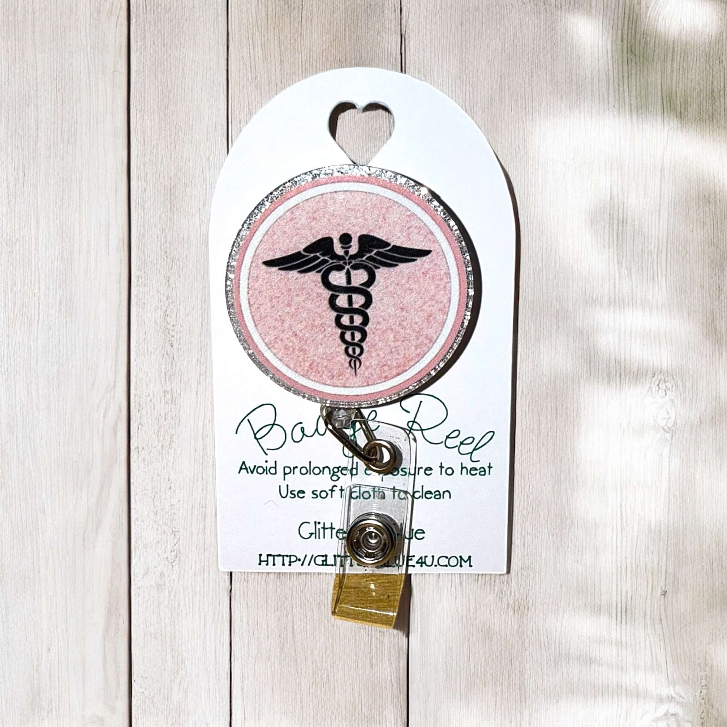 Nurse circular badge reel with pink glitter and nurse emblem, perfect accessory for nursing uniforms.