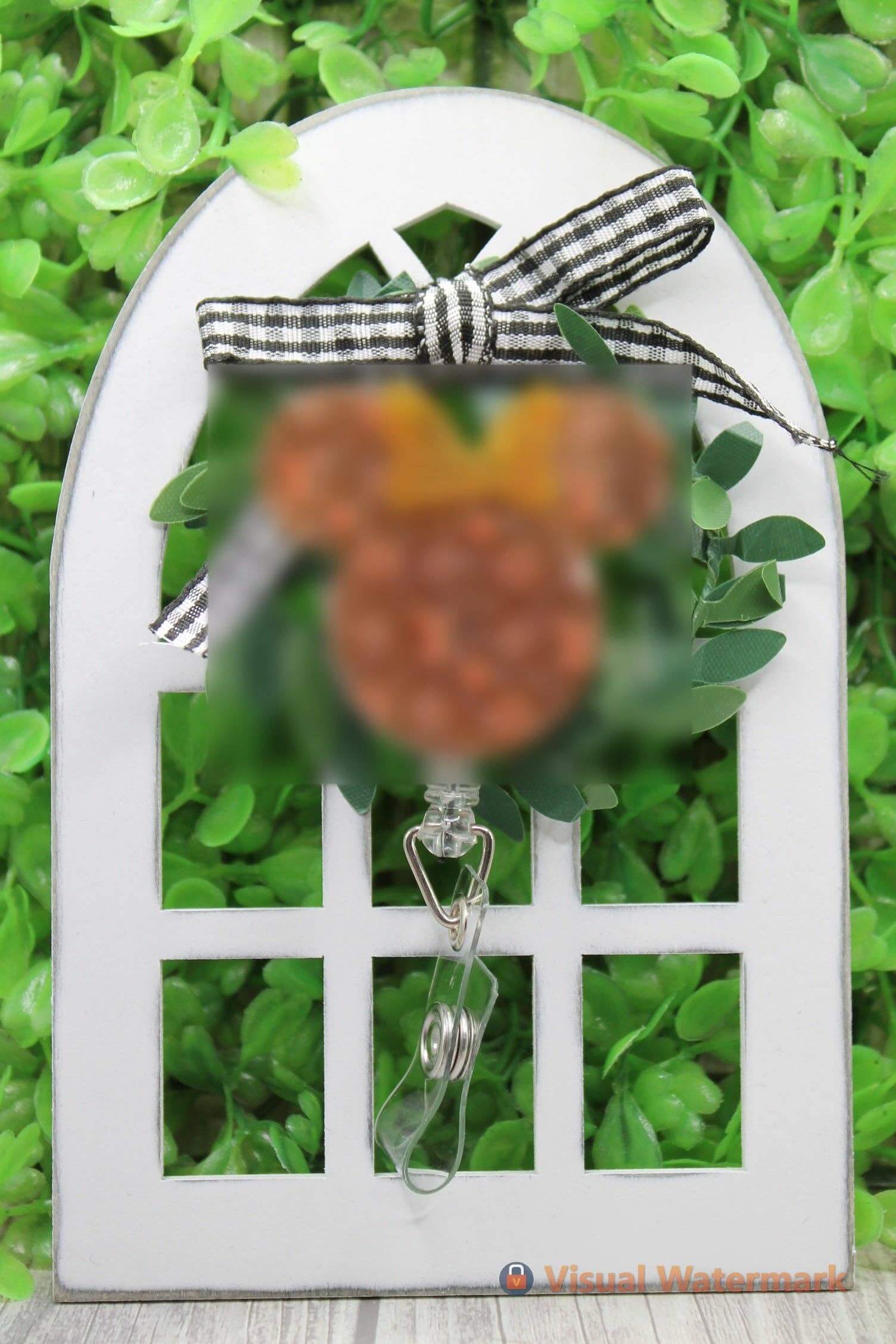 Mouse shaped badge reel with designer logo and alligator clip on decorative display.