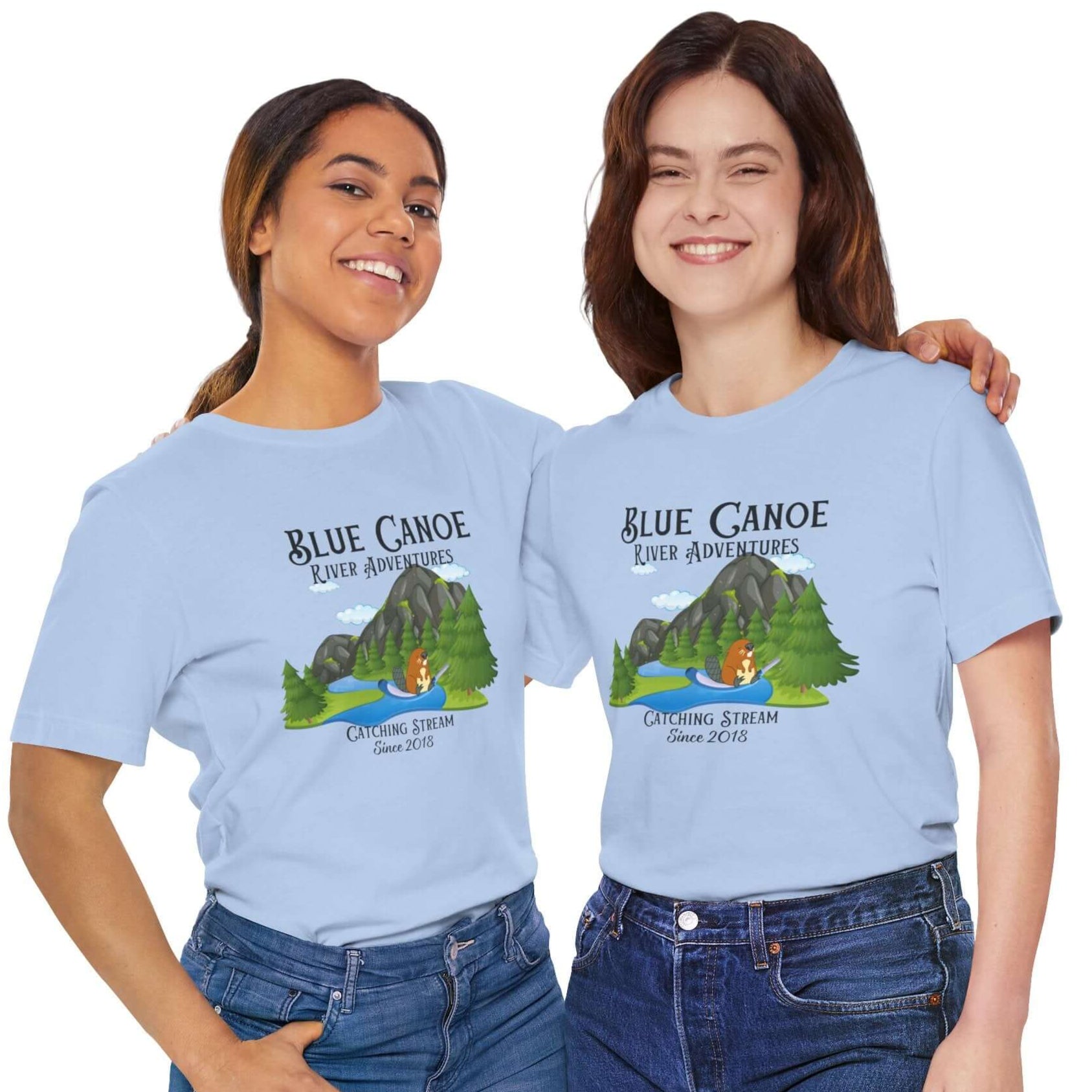 Two women wearing light blue t-shirts with 'Blue Canoe River Adventures' graphic and text, showcasing outdoor fun.